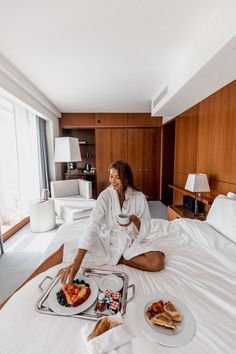 a woman sitting on top of a bed with food