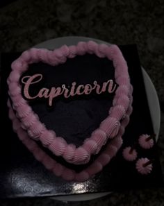 a heart shaped cake with the word capricorn written in pink frosting on it