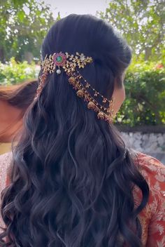 a woman with long black hair wearing a gold head piece