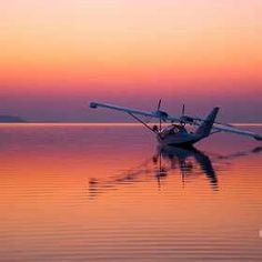 an airplane is sitting on the water at sunset