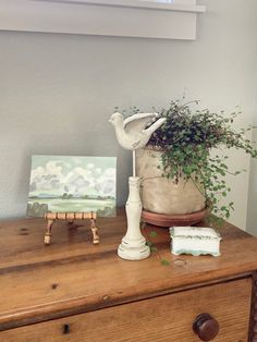 a potted plant sitting on top of a wooden dresser next to a small painting