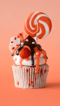 there is a cupcake with candy and lollipops on top that are drizzled with chocolate