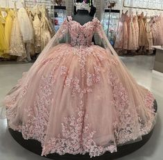 a pink ball gown is on display in a store, with other dresses behind it