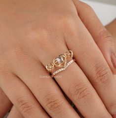 a woman's hand wearing a gold ring with two hearts on the middle finger