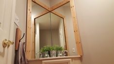 a bathroom mirror sitting above a sink under a wooden framed mirror over a white door