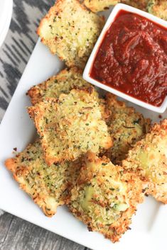 some fried food on a white plate with ketchup in a small bowl next to it