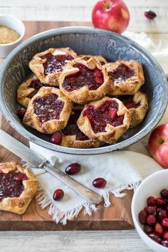 fresh baked pastries in a pie pan on a cutting board next to bowls of cherries