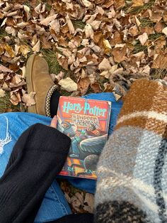 a person laying on the ground with their feet up next to a harry potter book