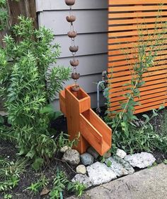 a garden with rocks and plants next to a wooden structure on the side of a house