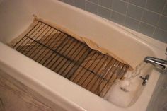 a bathtub filled with water next to a tiled wall