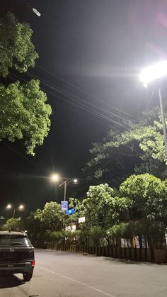 a car is parked on the side of the road at night with street lights in the background