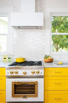 a white stove top oven sitting inside of a kitchen next to yellow cabinets and drawers