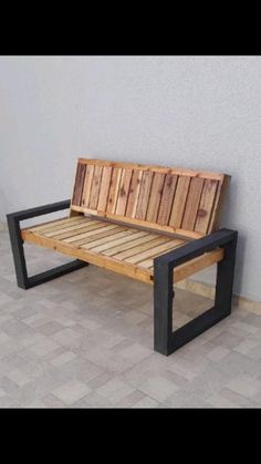 a wooden bench sitting on top of a tiled floor next to a gray wall with black frame