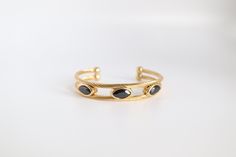 This Gold With Black Stone Stations Cuff Bracelet is a stunning addition to any jewelry collection. Crafted with high-quality gold and adorned with sleek black stones, this cuff bracelet adds a touch of elegance and sophistication to any outfit. Each stone is perfectly placed to catch the light, creating a dazzling effect that will surely turn heads. Elevate your style with this timeless and versatile bracelet. Elegant Black Bracelet With Strap, Elegant Black Jewelry With Bracelet Strap, Elegant Black Bracelets, Elegant Black Bangle Bracelet, Classic Black Bangle Bracelet, Classic Black Bangle Bracelets, Classic Black Bangle As Gift, Classic Black Cuff Bracelet Bangle, Classic Black Cuff Bracelet In Bangle Style