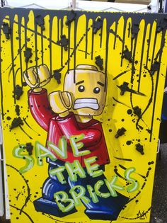 a yellow sign with graffiti on it that says save the bricks and a cartoon character holding a baseball bat