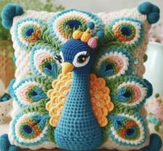 a crocheted peacock pillow sitting on top of a table