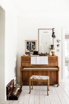 an old piano is in the corner of a room with white walls and wood floors