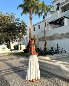 a woman in a white dress standing next to palm trees