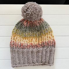 a multicolored knitted hat with a pom - pom on top