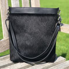 Crafted from black hair on cowhide on the front and soft, black leather on the back, the Gossan handbag is a stylish, versatile day to evening bag.  Dimensions: Height: 30cm (11.8in) Width at widest part: 26cm (10.2in) Depth at deepest part: 7cm (2.8in) This is a handmade item so measurements may vary from approx. 0.5-1cm. Features; Black and white spotty, cotton lining with an inside zipped pocket and a handy phone pocket. Secured with a magnetic snap closure. Silver coloured Italian metal fixi Black Leather Hobo Bag With Mobile Phone Holder, Leather Hobo Bag With Mobile Phone Pocket For Evening, Cowhide Purse, Black Cow, Cow Skin, Handbag Black, Purse Black, Soft Black, Leather Handbag