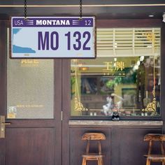 two wooden stools sit in front of a restaurant with a sign that reads mo132