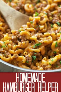 a skillet filled with macaroni and cheese being stirred by a wooden spoon