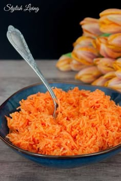 a blue bowl filled with shredded carrots and a spoon