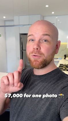 a man with a bald head is pointing at the camera while wearing a t - shirt that says $ 7, 000 for one photo