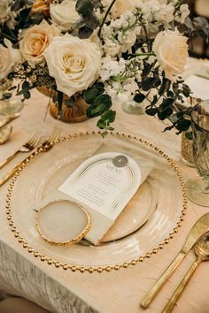 an elegant table setting with white flowers and gold place settings