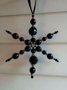 a black beaded snowflake hanging on a wall