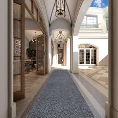 an empty hallway with blue carpeting and large windows on both sides, leading to the front door