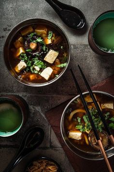 three bowls of soup with chopsticks on the side