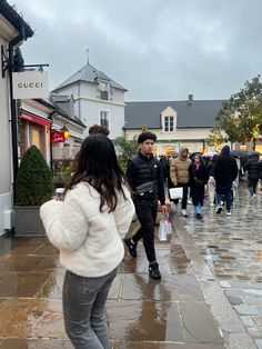 people are walking down the street on a rainy day