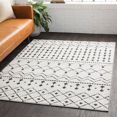 a white and black rug in a living room next to a brown leather couch on the floor