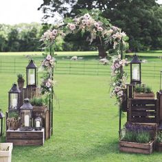 several wooden crates with flowers and lanterns on them in the middle of a grassy field