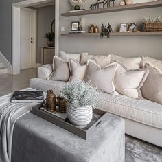 a living room filled with white furniture and lots of shelves on the wall above it