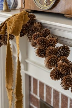 pine cones are hanging from the mantle in front of a clock