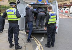 three police officers are loading the back of a van