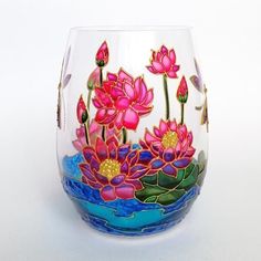 a glass vase with flowers painted on the side and water in the bottom, sitting on a white surface