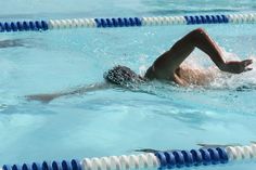 a man is swimming in the pool with his feet on the water's edge