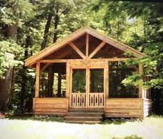 a small wooden cabin in the middle of some trees and grass with porches on each side