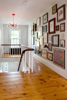 a staircase with many framed pictures on the wall and wood flooring in front of it