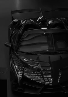 the front end of a red sports car in a dark room with its hood up