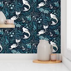 a blue wallpaper with white mermaids and stars in the background, along with two vases