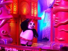 a panda bear is standing in front of some red and purple decorations