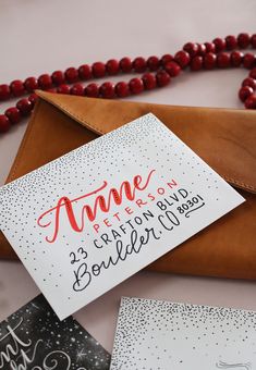 an envelope and some cards are on a table with bead necklaces around it