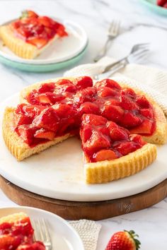 a strawberry tart on a plate with a slice cut out and ready to be eaten