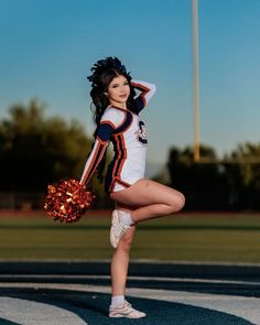 a cheerleader is posing on the field with her pom - poms in hand