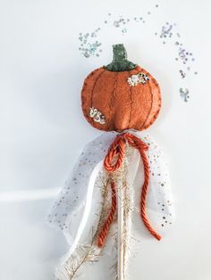 an orange pumpkin is sitting on top of a piece of white fabric with beads and sequins