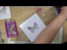 a person is working on some art work with purple and white butterfly stencils